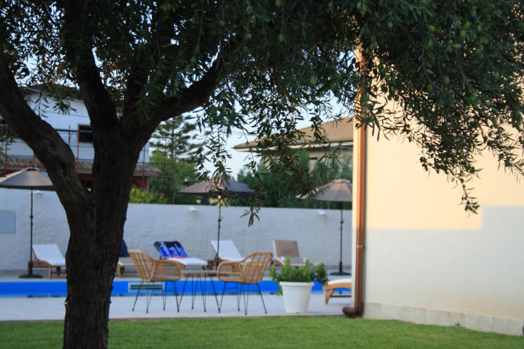 a patio with chairs and a table and a tree at Amada Hotel Siracusa in Melilli