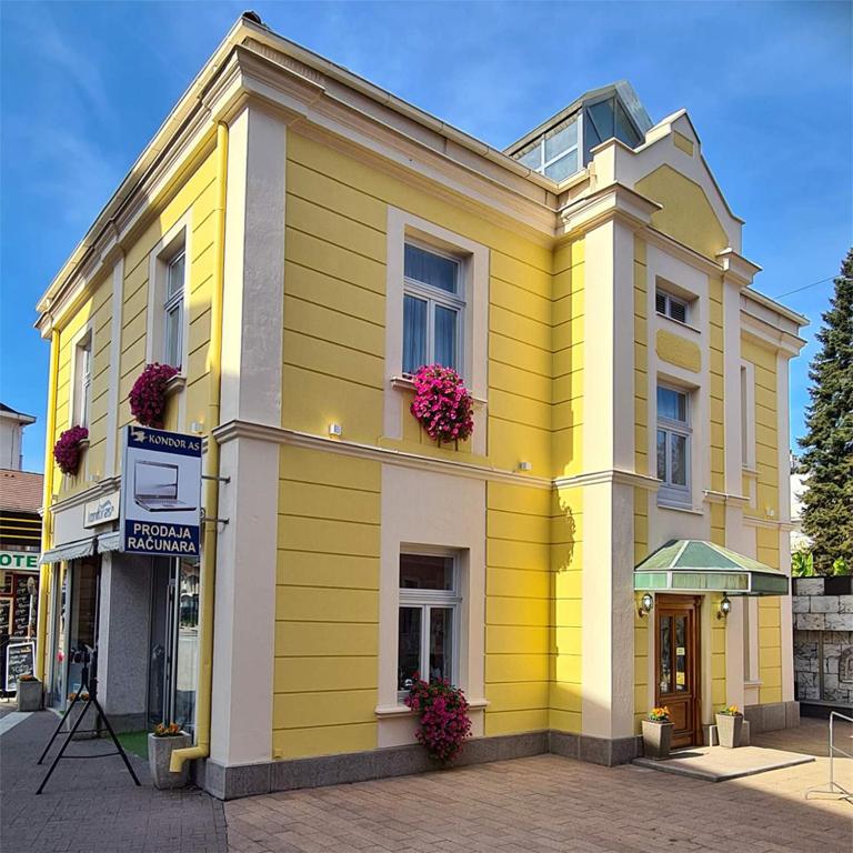 un edificio amarillo con flores en la ventana en KONDOR apartmani, en Vrnjačka Banja