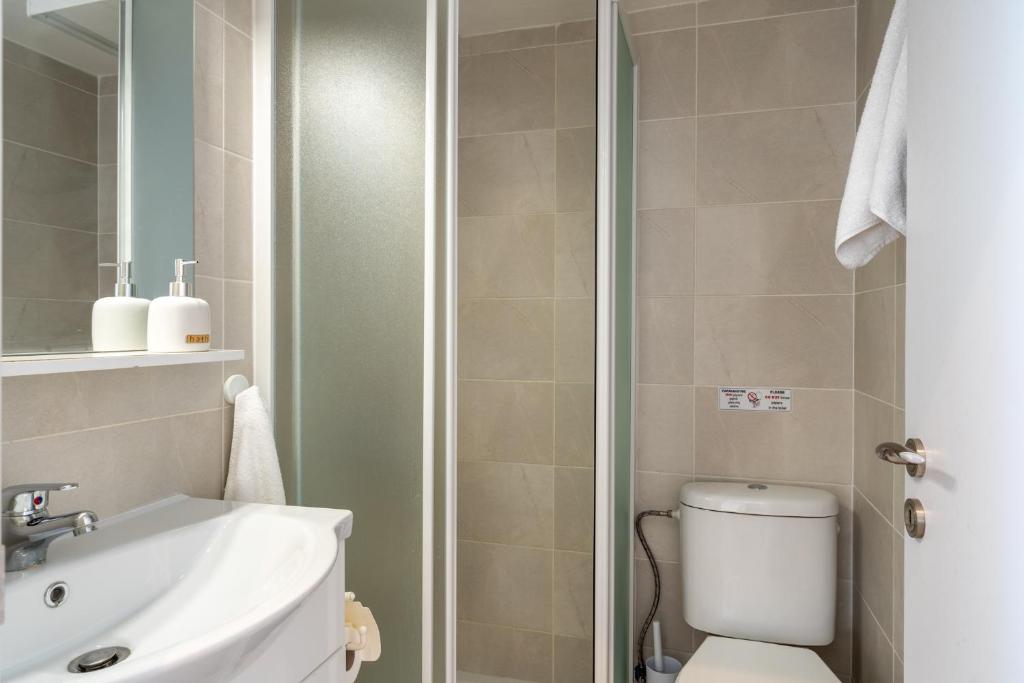 La salle de bains est pourvue de toilettes, d'un lavabo et d'une douche. dans l'établissement Orchid's Cozy Apartment in Larnaca, à Larnaka