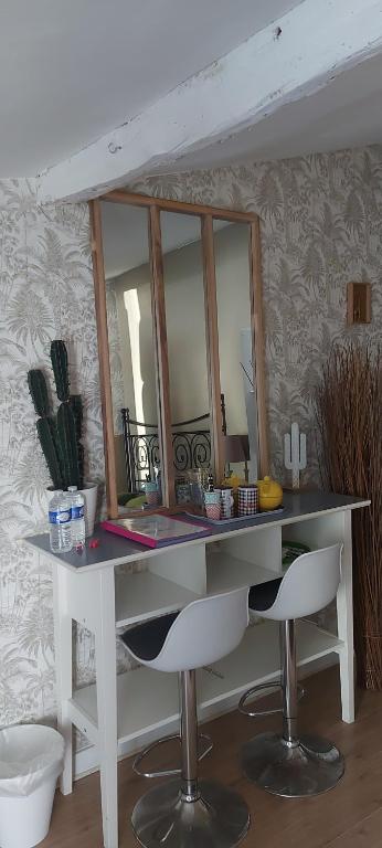 a bathroom counter with a mirror and two white chairs at Chez Margarett in Royan