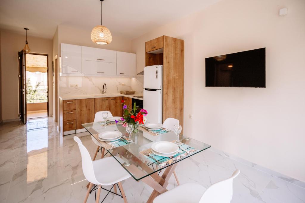 a kitchen with a glass table and white chairs at Nadia Apartments B in Kalamaki