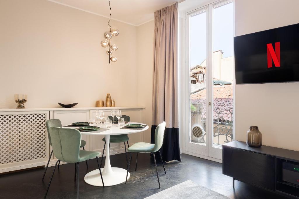 uma sala de jantar com uma mesa e cadeiras e uma janela em HL Luxury Apartment - Duomo, Via Torino, Montenapoleone em Milão