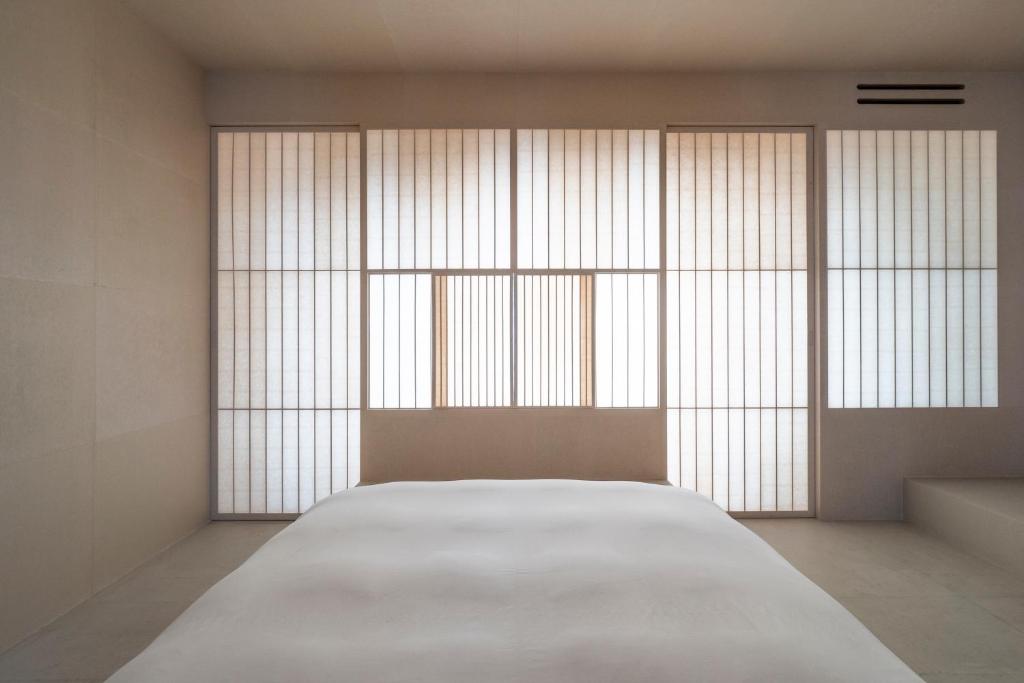 a bed in a room with large windows at LOG in Onomichi