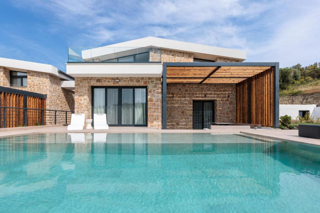 a house with a swimming pool in front of a house at Five Senses Of Luxury in Kalandra