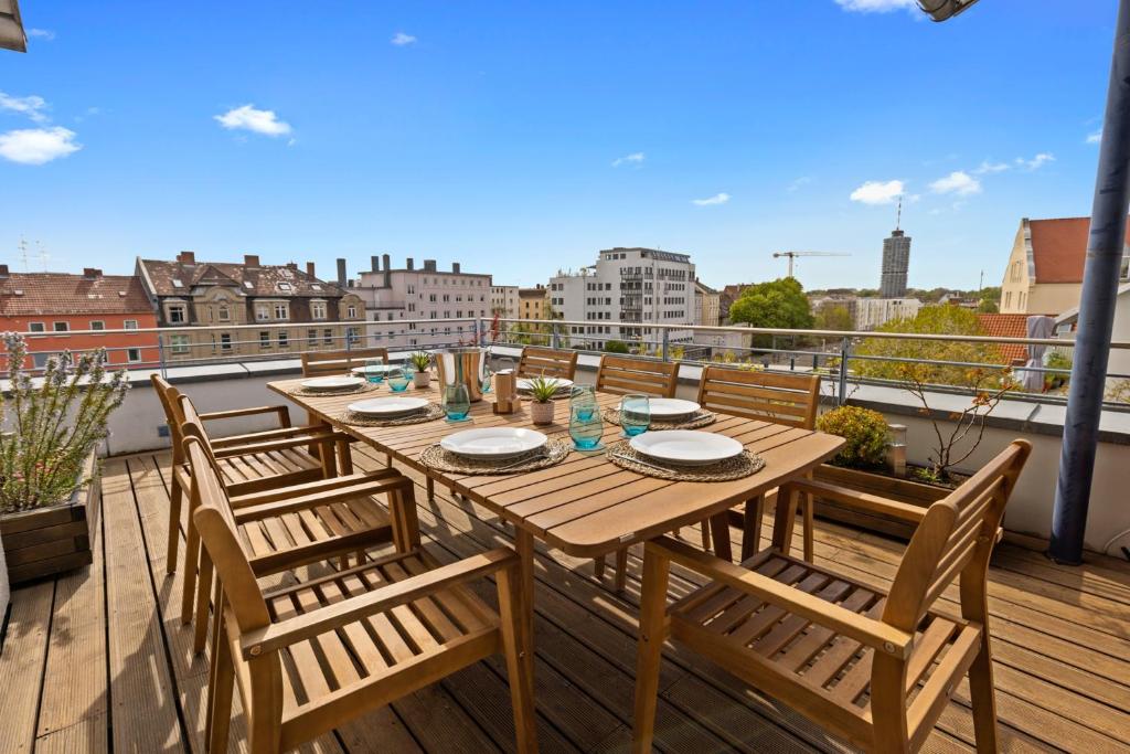 d'une table et de chaises en bois sur un balcon avec vue. dans l'établissement Arbio I Premium Penthouse Apartment Augsburg, à Augsbourg