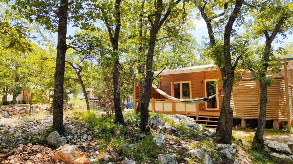 eine Blockhütte mit einer Hängematte im Wald in der Unterkunft Camping Rives du Lac de Sainte Croix in Bauduen