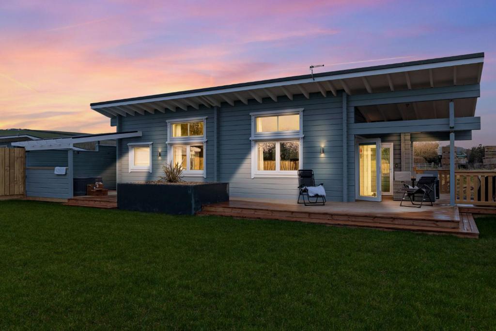 ein kleines blaues Haus mit einer Terrasse im Hof in der Unterkunft Croftner, Great Field Lodges in Braunton