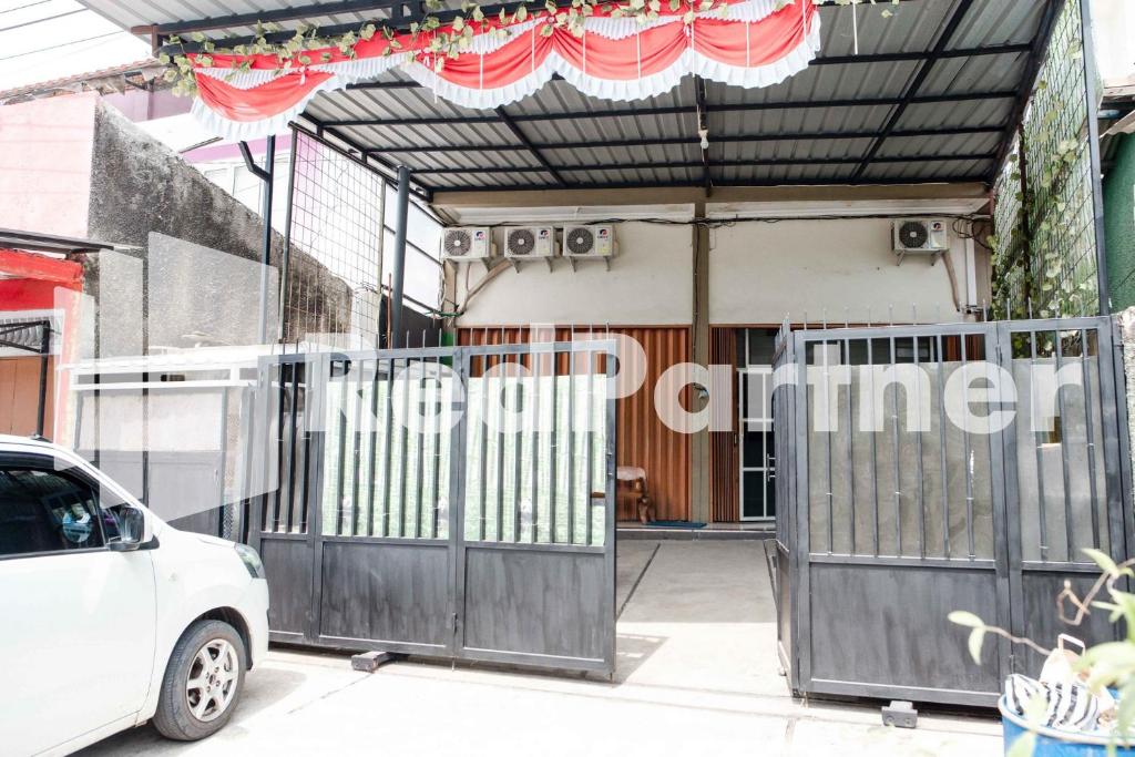 a white car parked in front of a building with a gate at Happy Inn Puspo Mitra RedDoorz in Jomblang