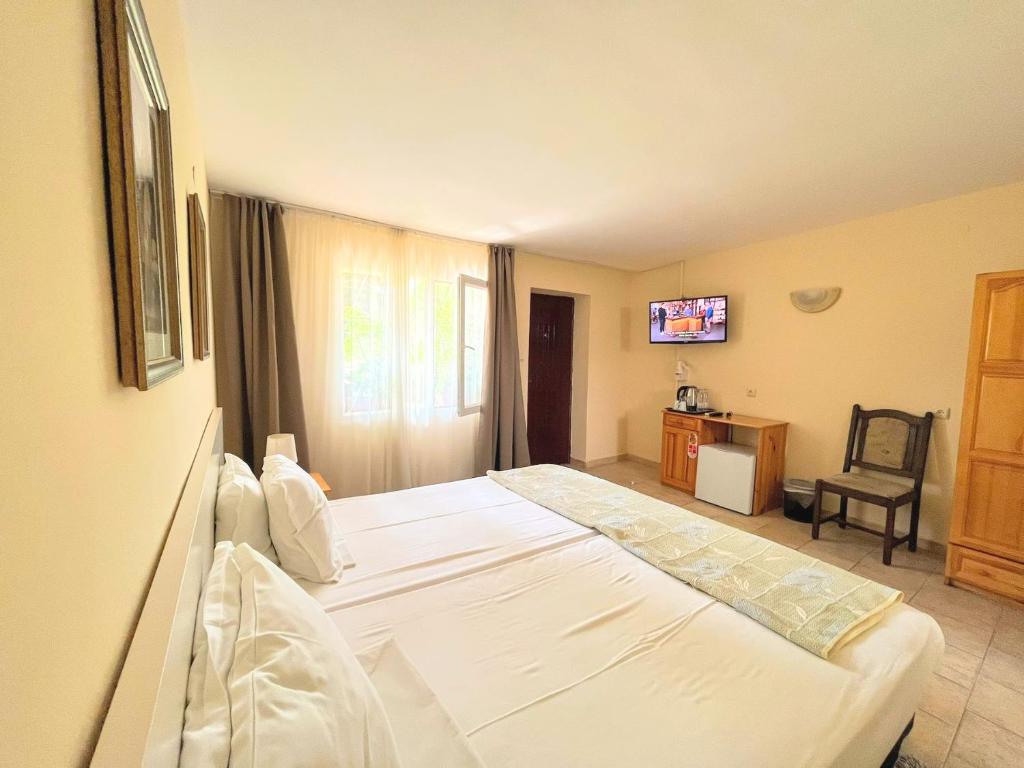 a bedroom with a large white bed and a chair at Lotus Family Hotel - Free Parking in Sunny Beach