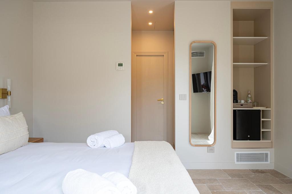 a white bedroom with a bed and a mirror at Lou Cagnard in Saint-Tropez