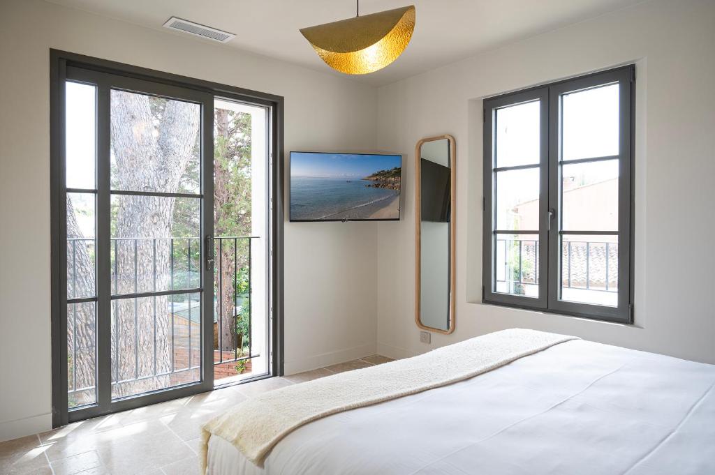 a white bedroom with large windows and a bed at Lou Cagnard in Saint-Tropez