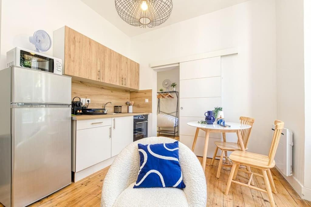 a kitchen with a table and chairs and a refrigerator at 2 pièces tout confort, déco moderne, wifi fibre in Grenoble