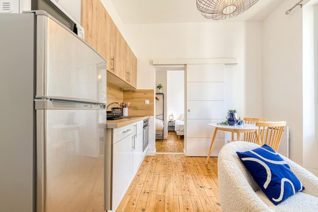 a kitchen with a stainless steel refrigerator and a table at 2 pièces tout confort, déco moderne, wifi fibre in Grenoble