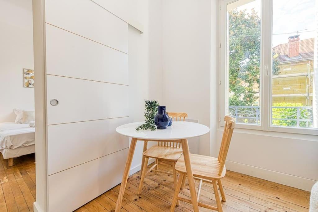 a small white table and chairs in a room with a window at 2 pièces tout confort, déco moderne, wifi fibre in Grenoble