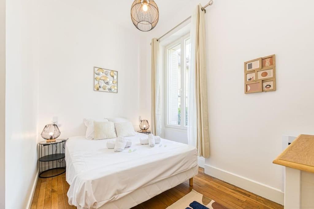 a white bedroom with a bed and a window at 2 pièces tout confort, déco moderne, wifi fibre in Grenoble
