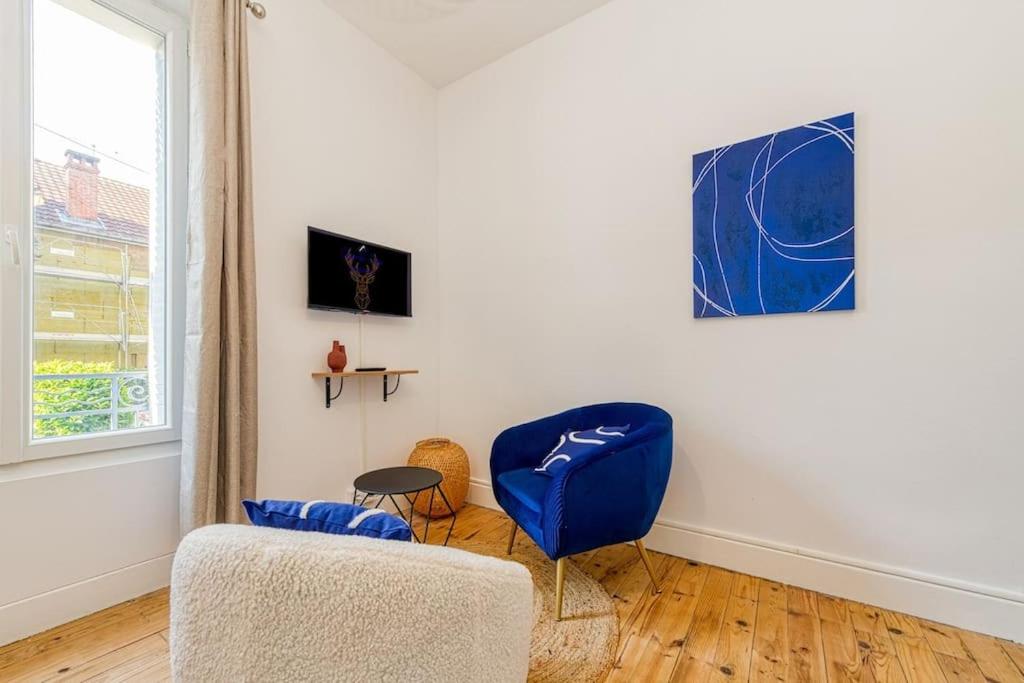 a living room with a blue chair and a couch at 2 pièces tout confort, déco moderne, wifi fibre in Grenoble