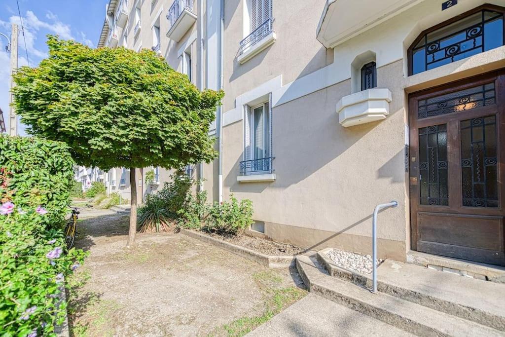 a building with a wooden door and a tree at 2 pièces tout confort, déco moderne, wifi fibre in Grenoble