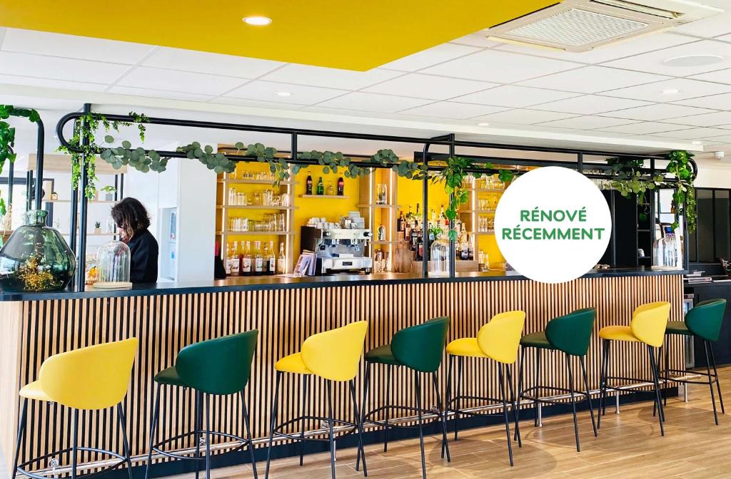 - un bar avec des chaises jaunes et vertes dans la pièce dans l'établissement Campanile Bollène A7, à Bollène