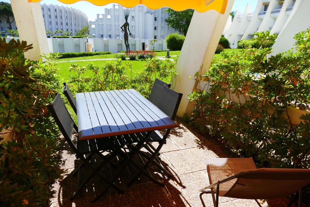 une table et des chaises assises sur une terrasse dans l'établissement T2 Rez-de-jardin, terrasse et parking, proche de la plage, à La Grande Motte