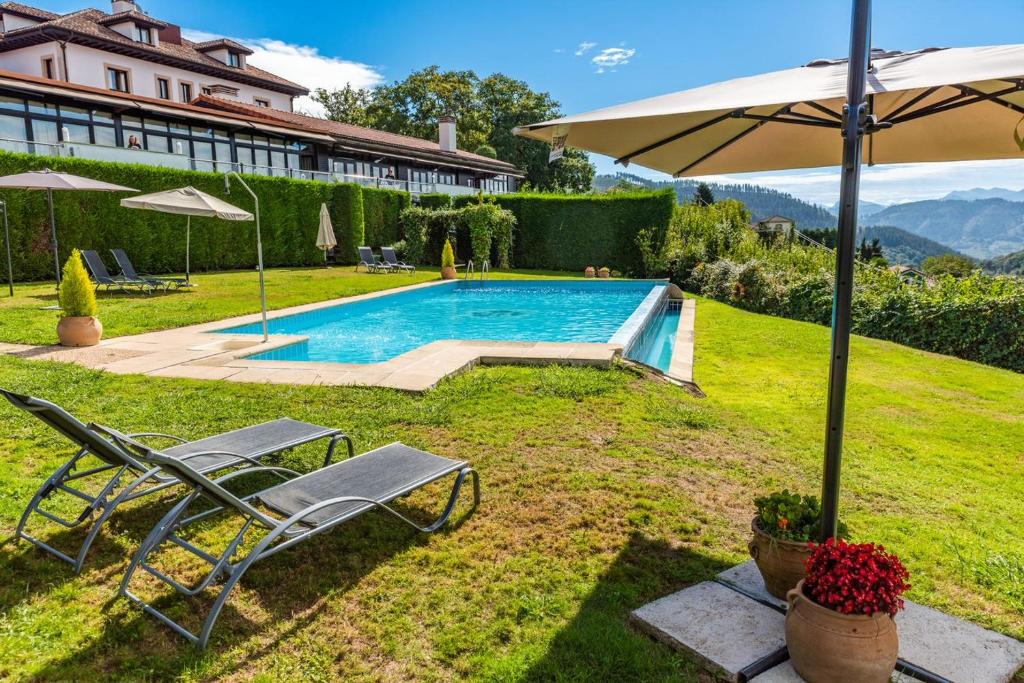 einen Pool mit zwei Liegestühlen und einem Sonnenschirm in der Unterkunft Hosteria de Torazo Nature Hotel & Spa in Torazo