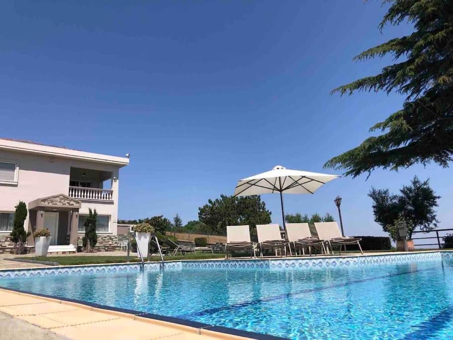 a swimming pool with chairs and an umbrella at Villa Casa Chrissy in Plagiárion