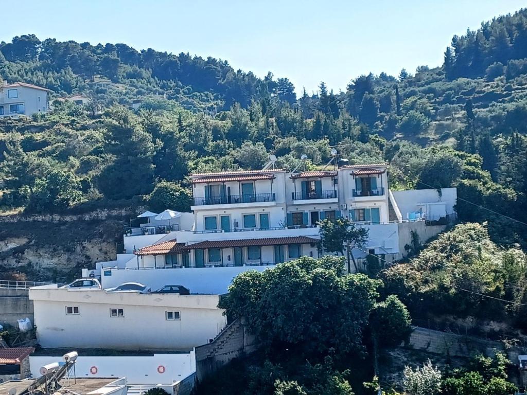 een groot wit gebouw bovenop een heuvel bij Pension Anna in Patitiri