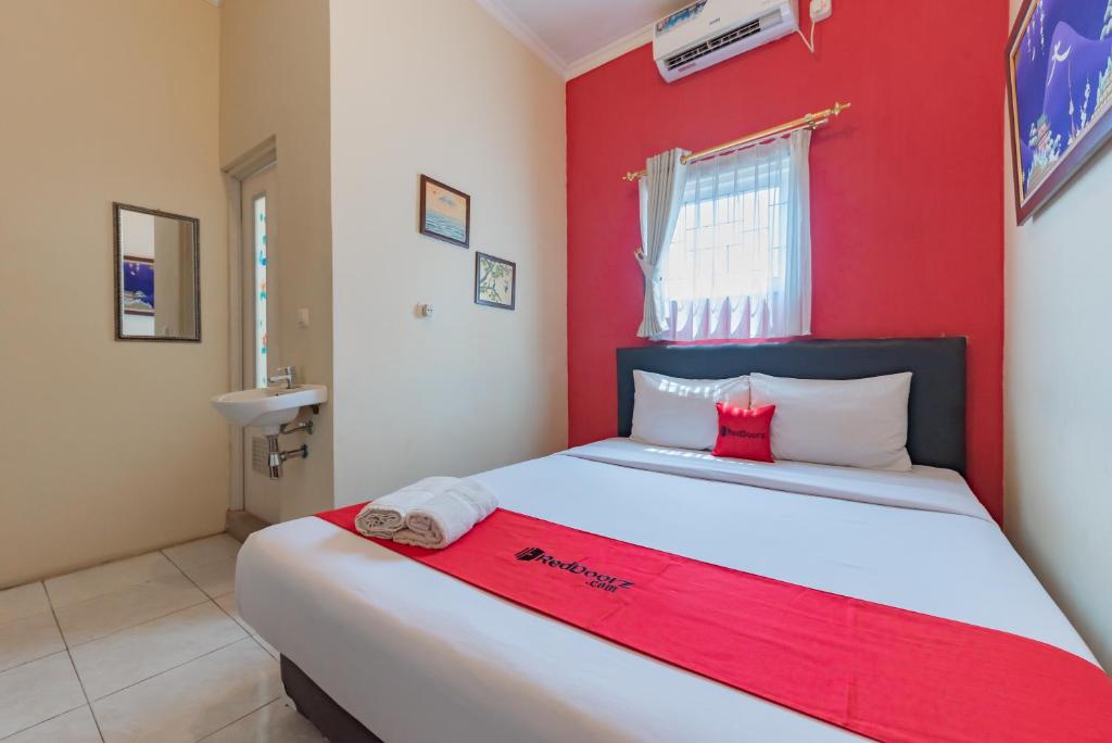 um quarto com uma cama grande e uma parede vermelha em RedDoorz Syariah at Sudirman Street Garut em Garut