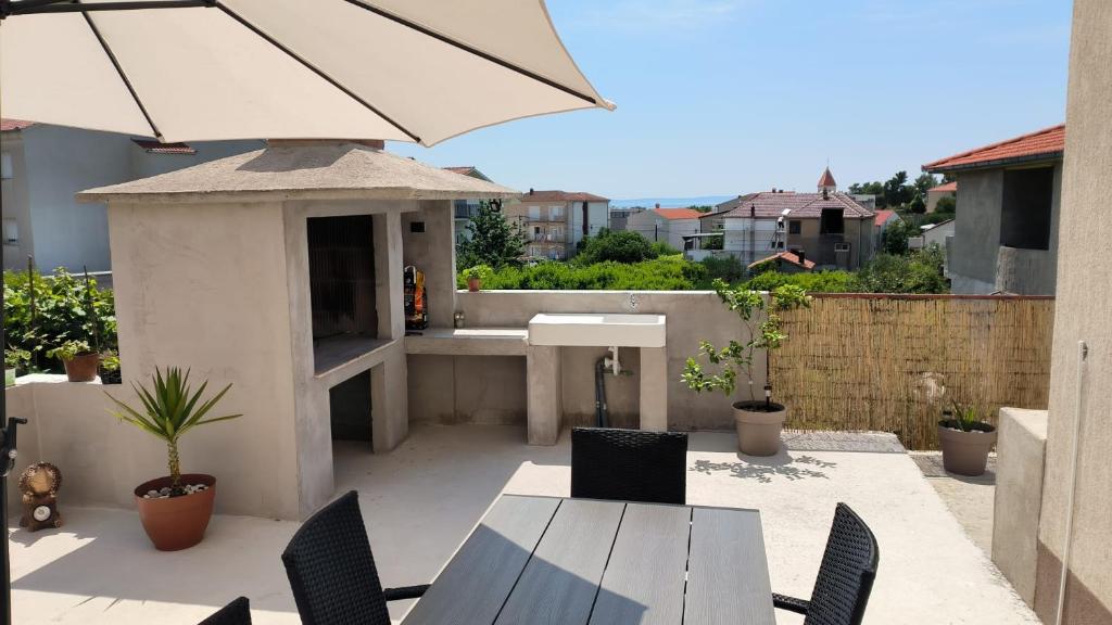 een patio met een tafel en stoelen en een parasol bij Apartment Ruby in Podstrana