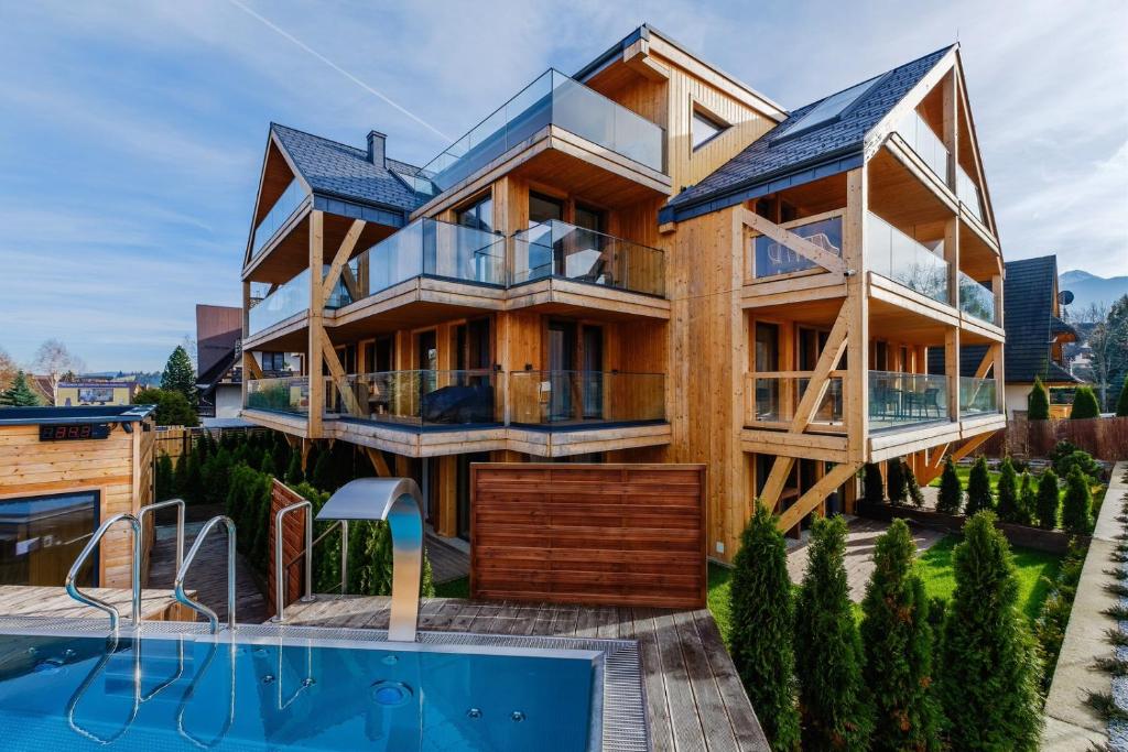 uma casa com uma piscina em frente em Apartament RELAKS - komfortowy apartament z bezpłatnym jacuzzi, sauną oraz podziemnym parkingiem w cenie em Zakopane