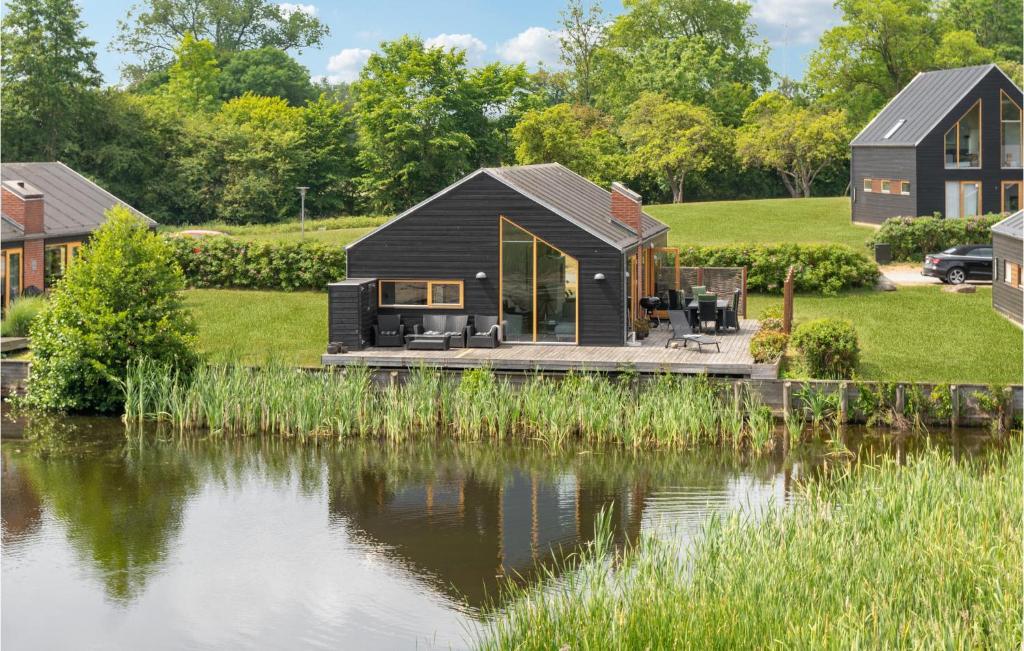 a black house with a deck next to a body of water at Awesome Home In Stubbekbing With Kitchen in Stubbekøbing