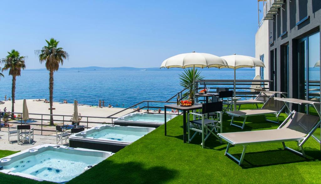 a patio with chairs and tables and a view of the ocean at Via Mare Luxury Rooms in Split