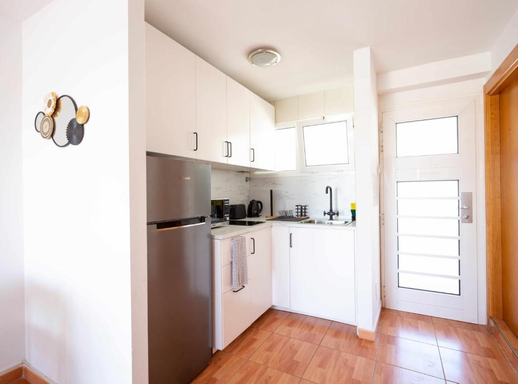 a kitchen with white cabinets and a wooden floor at Apartamento Maypa 5 Mar in Meloneras