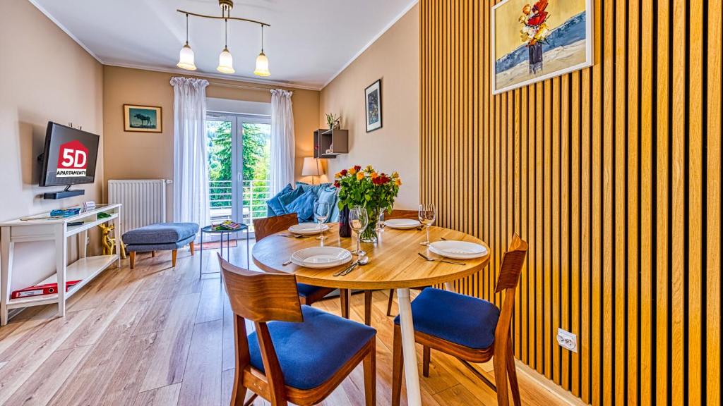 a dining room with a wooden table and blue chairs at Apartament Lazurowy - 5D Apartamenty in Świeradów-Zdrój