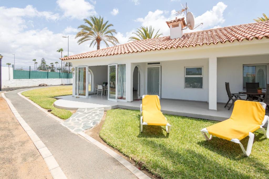 een huis met twee gele stoelen in de tuin bij Lightbooking Sun Club deluxe Playa del Ingles in Playa del Inglés