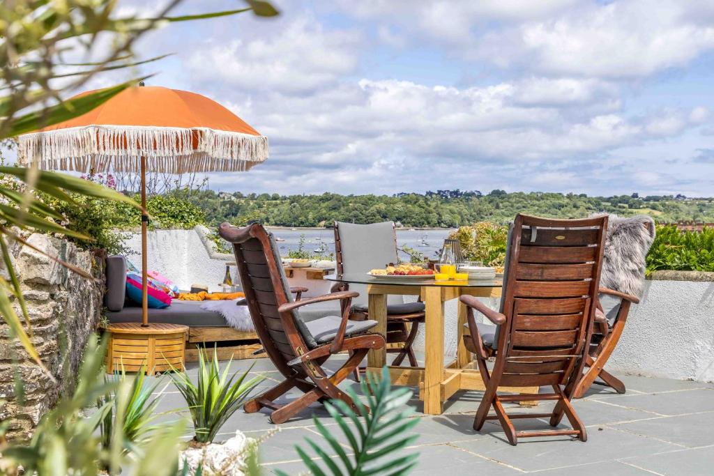 a patio with a table and chairs and an umbrella at Crooks Cottage - Charming, characterful, glorious views from the garden in Dittisham