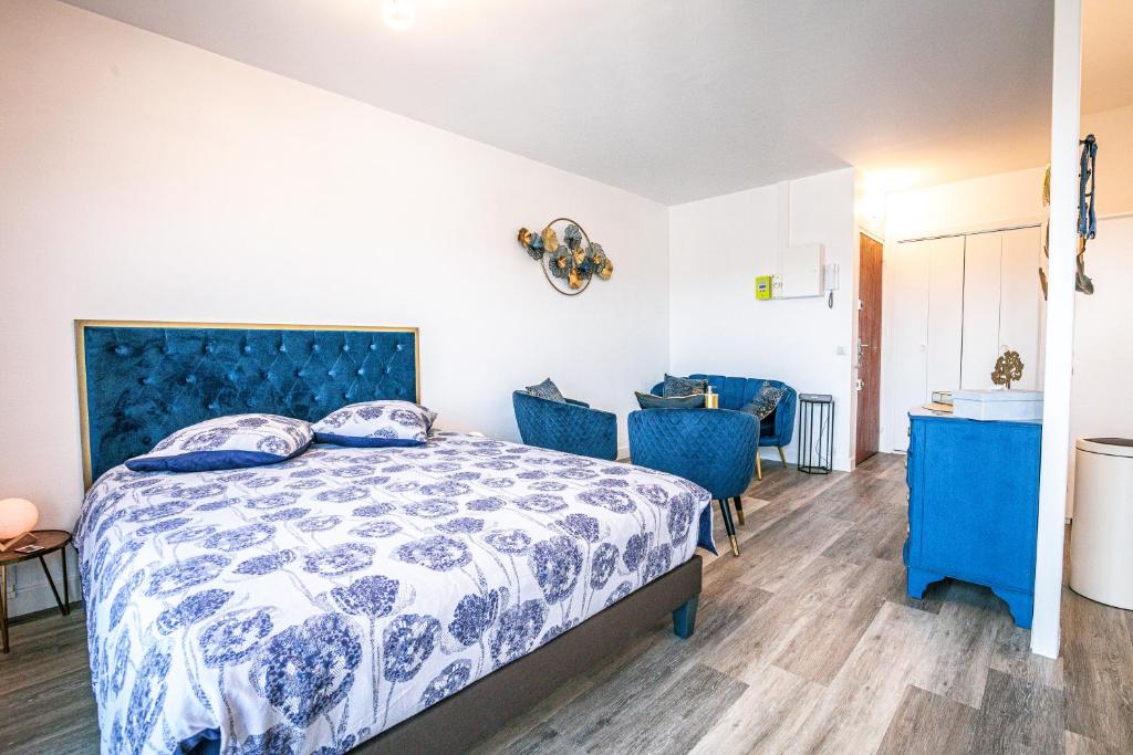 - une chambre avec un lit et deux chaises bleues dans l'établissement Blue Gold - Saint Rémi - Basilique, à Reims