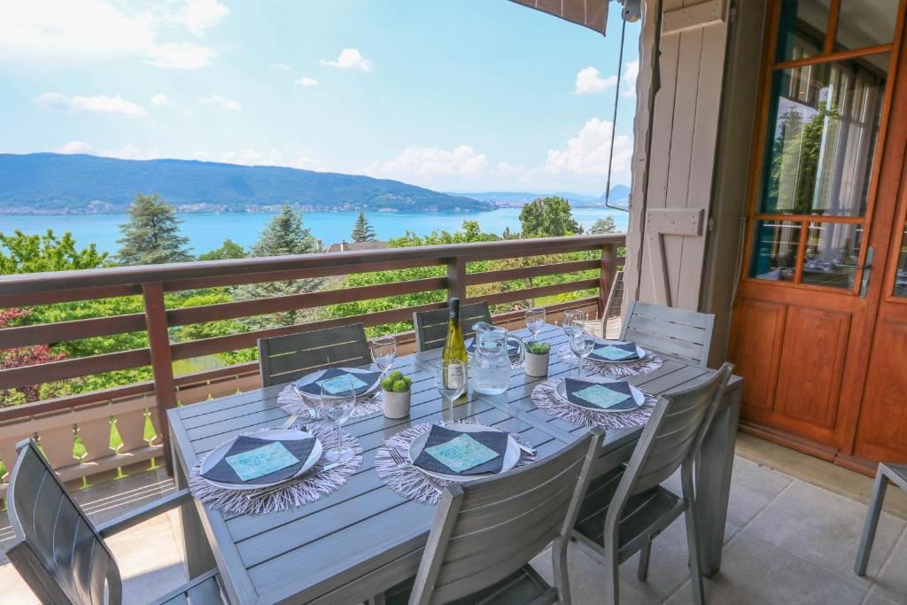 a table on a balcony with a view of the water at La Villa des Grillons, outstanding lake view and private garden - LLA Selections by Location Lac Annecy in Veyrier-du-Lac