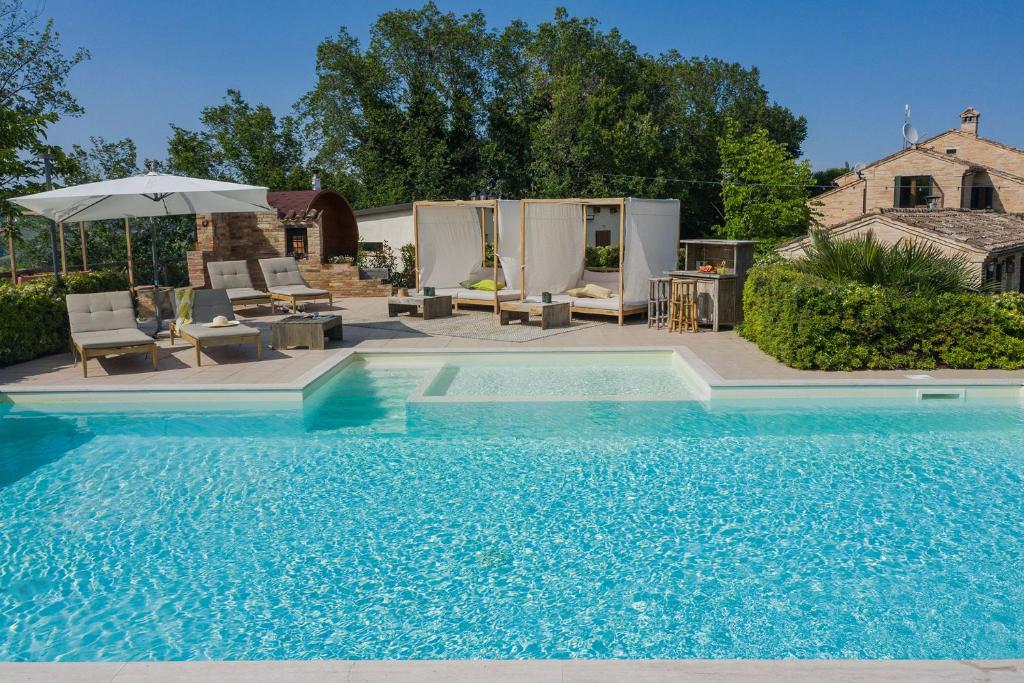una gran piscina con sillas y sombrilla en Villa Sky 14 en Massa Fermana