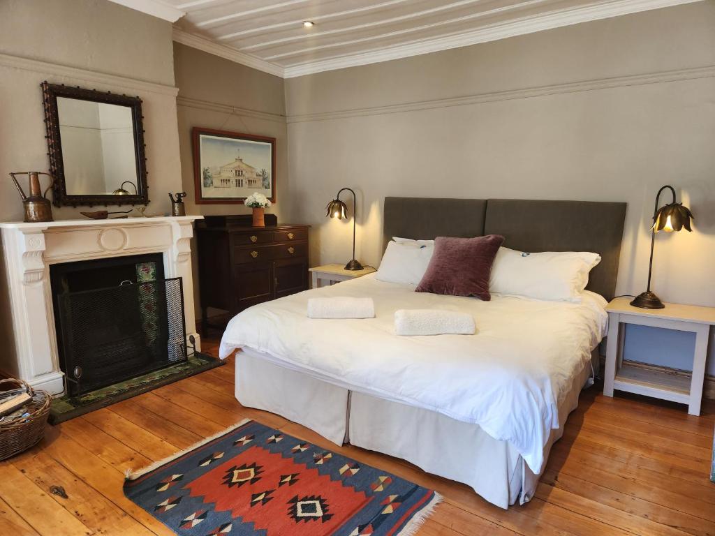 a bedroom with a large bed and a fireplace at Wishford Cottage on Worcester in Grahamstown