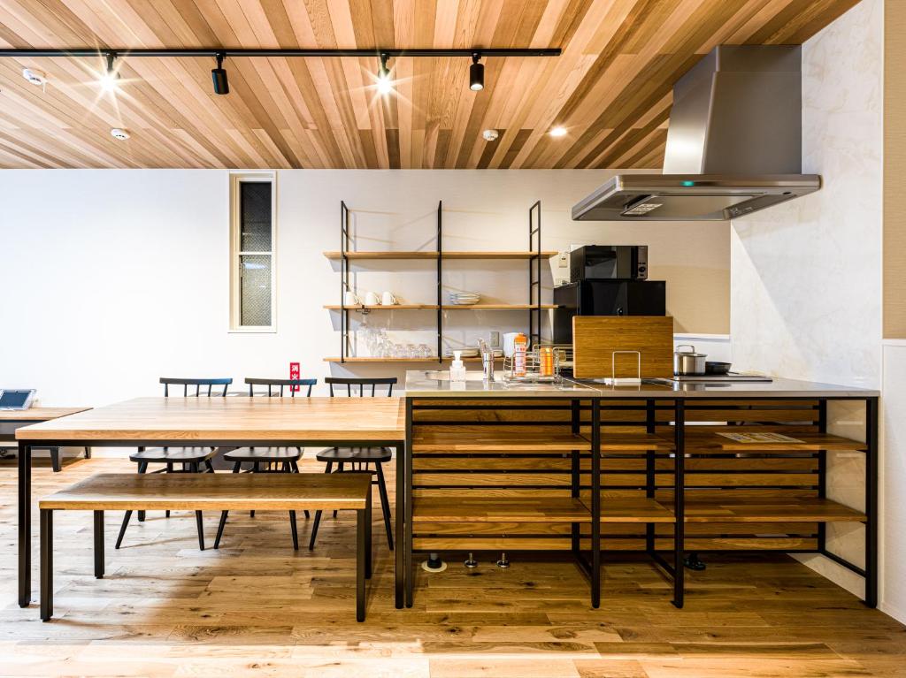 eine Küche mit Holzdecken, einem Tisch und Bänken in der Unterkunft Rakuten STAY HOUSE x WILL STYLE Hagi Nishitamachi in Hagi