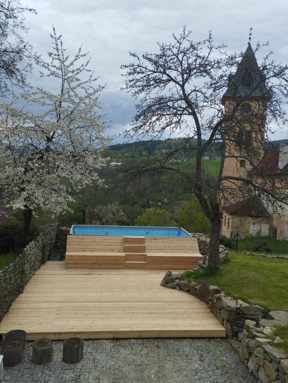 un ponte di legno con una torre dell'orologio sullo sfondo di Vila Anička Vimperk a Vimperk