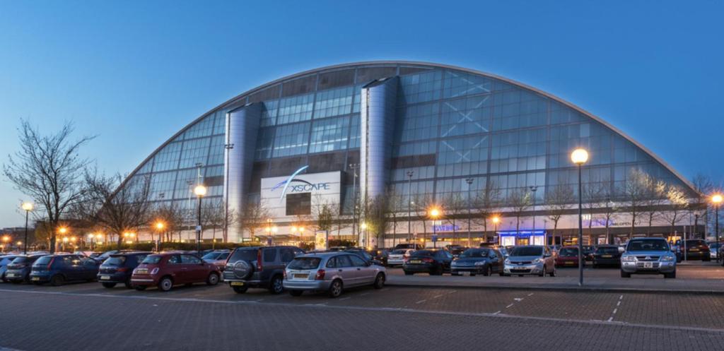 a large building with cars parked in a parking lot at Campbell Park apartment with a balcony and free parking in Milton Keynes