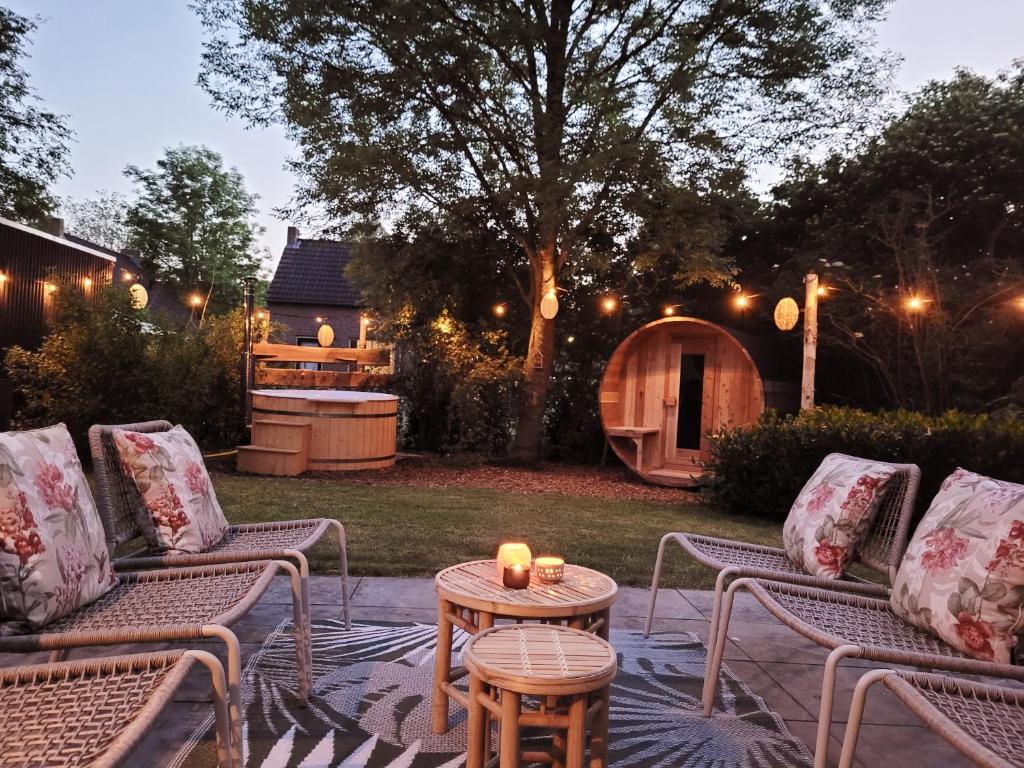 een patio met 2 stoelen en een tafel met kaarsen bij Bohemian Wellness met hottub & sauna in Ewijk