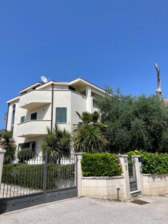 a white house with a fence in front of it at Seaside apartments in Kaštela