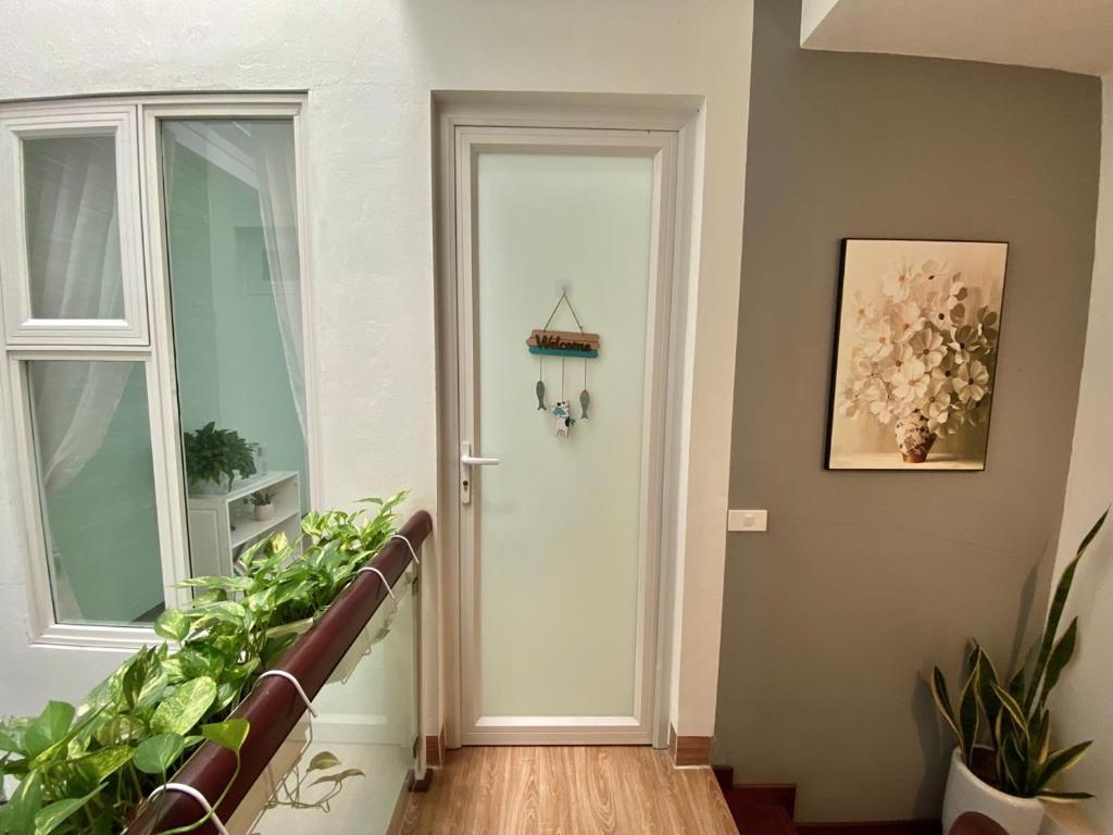 a hallway with a white door and some plants at Green Homestay in Hanoi