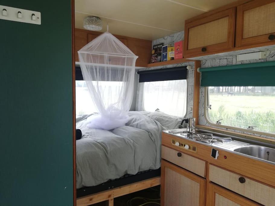 a bedroom with a bed with a net on it at Cute little caravan for 2 in old orchard in Hem