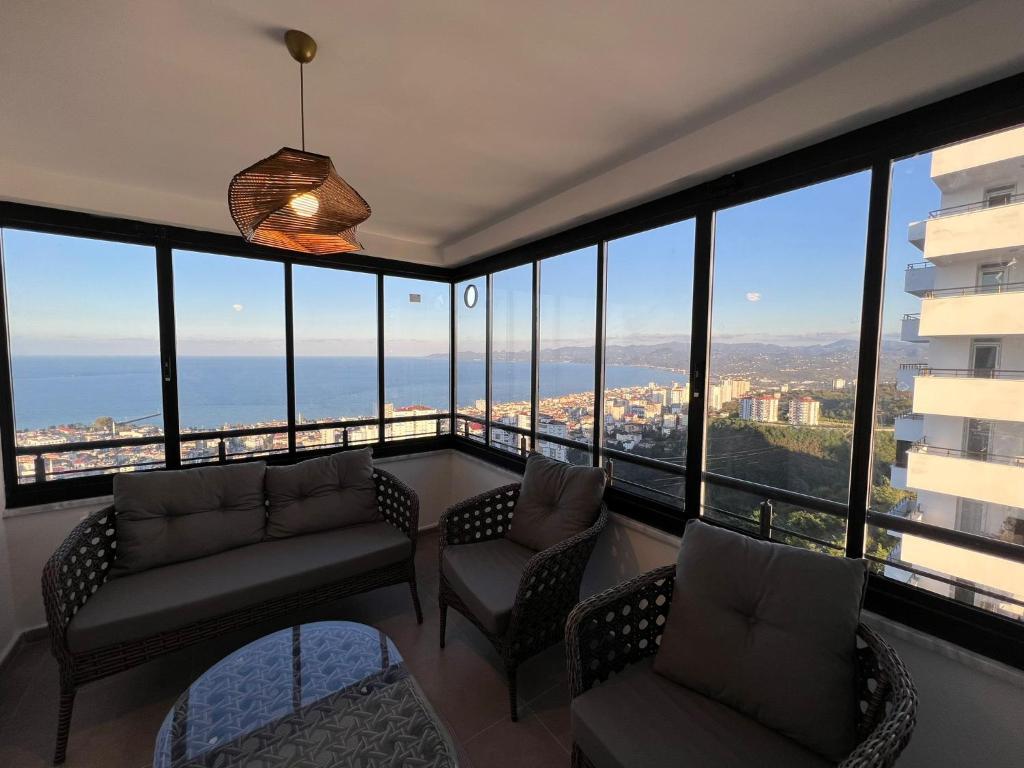 a living room with couches and chairs and large windows at Site içerisinde deniz manzaralı ve sahile yakın otopark sorunu bulunmayan kiralık daire in Fatsa