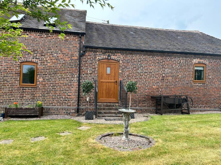 a brick house with a wooden door in a yard at Holmleigh Annexe in Tamworth