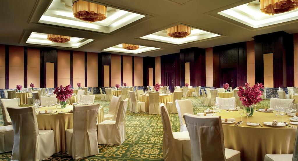 un salón de banquetes con mesas y sillas blancas en The Ritz - Carlton, Bangalore, en Bangalore