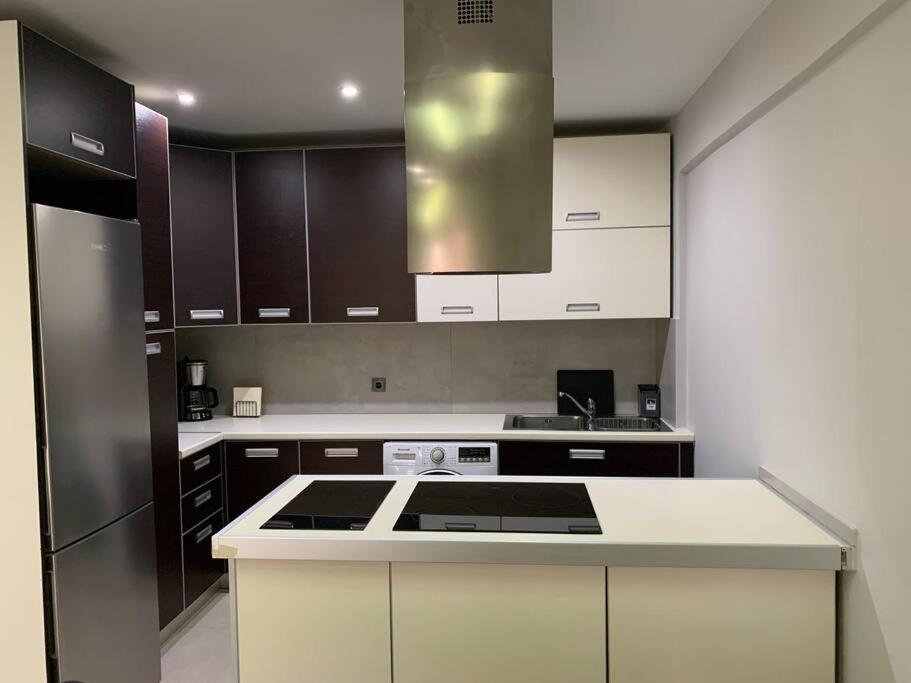a kitchen with white cabinets and a stove top oven at Varkiza Lux Apartment in Varkiza